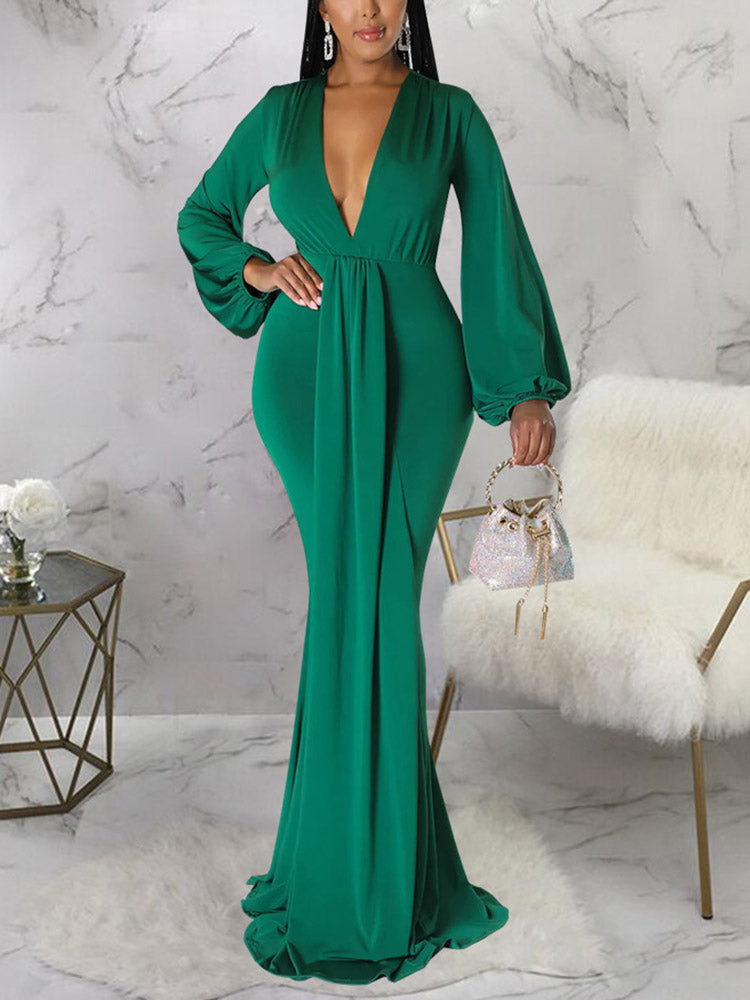Woman wearing a floor-length emerald green formal dress with bishop sleeves and a plunging V-neck.