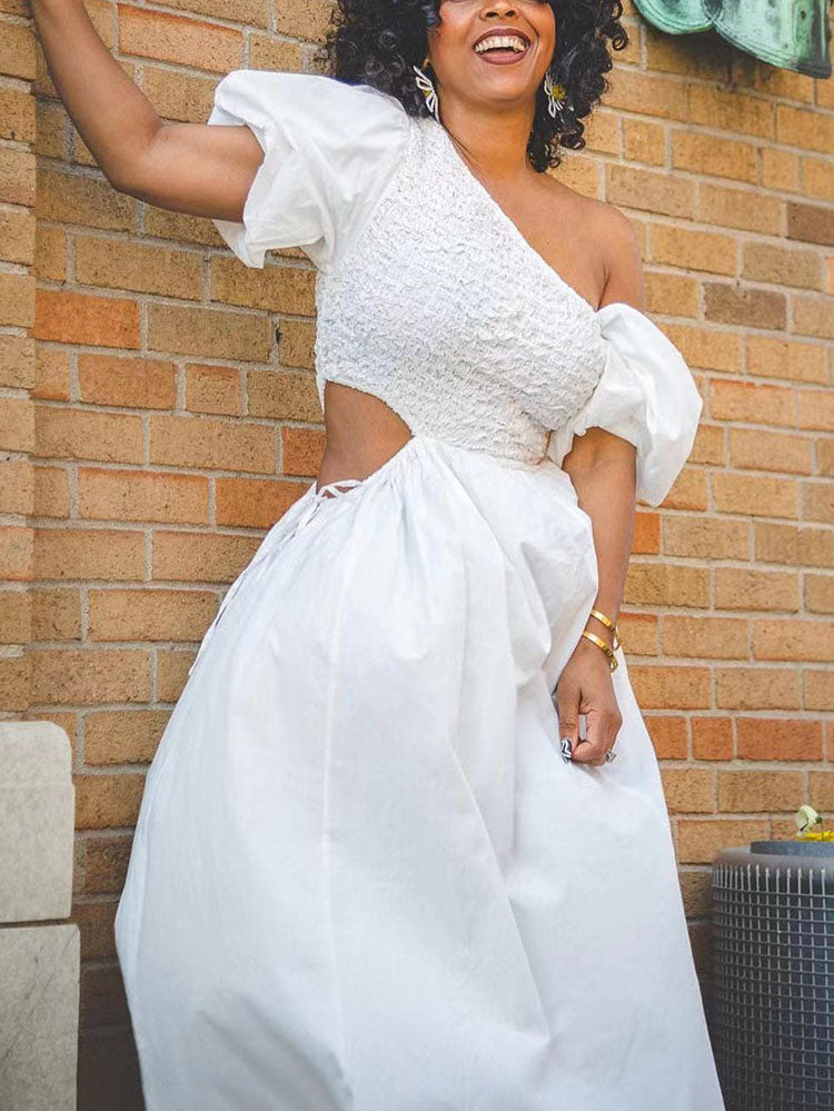 Woman posing in a white one-shoulder maxi dress with puff sleeves and a flowing skirt.