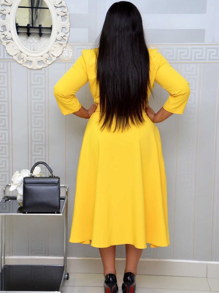 Back view of a woman in a yellow fit and flare dress with a flared skirt and three-quarter sleeves.