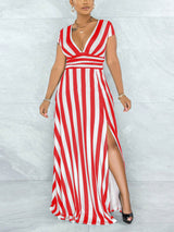 Woman wearing a red and white striped maxi dress with a V-neck and high slit, standing against a marble wall.