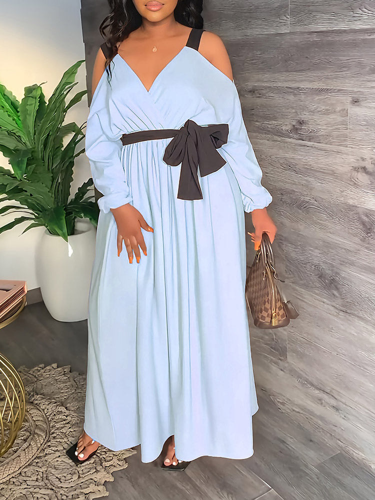 Woman wearing a long, off-the-shoulder light blue dress with a dark tie-waist belt.