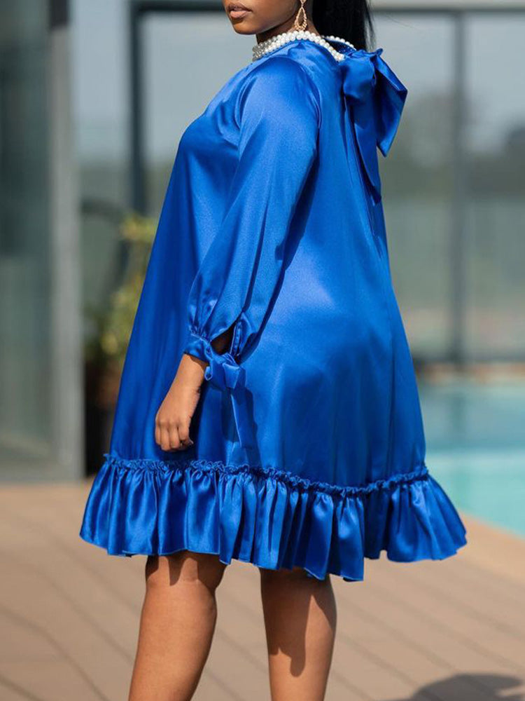 Back view of a royal blue satin dress with a keyhole closure and bow detail at the back of the neck.