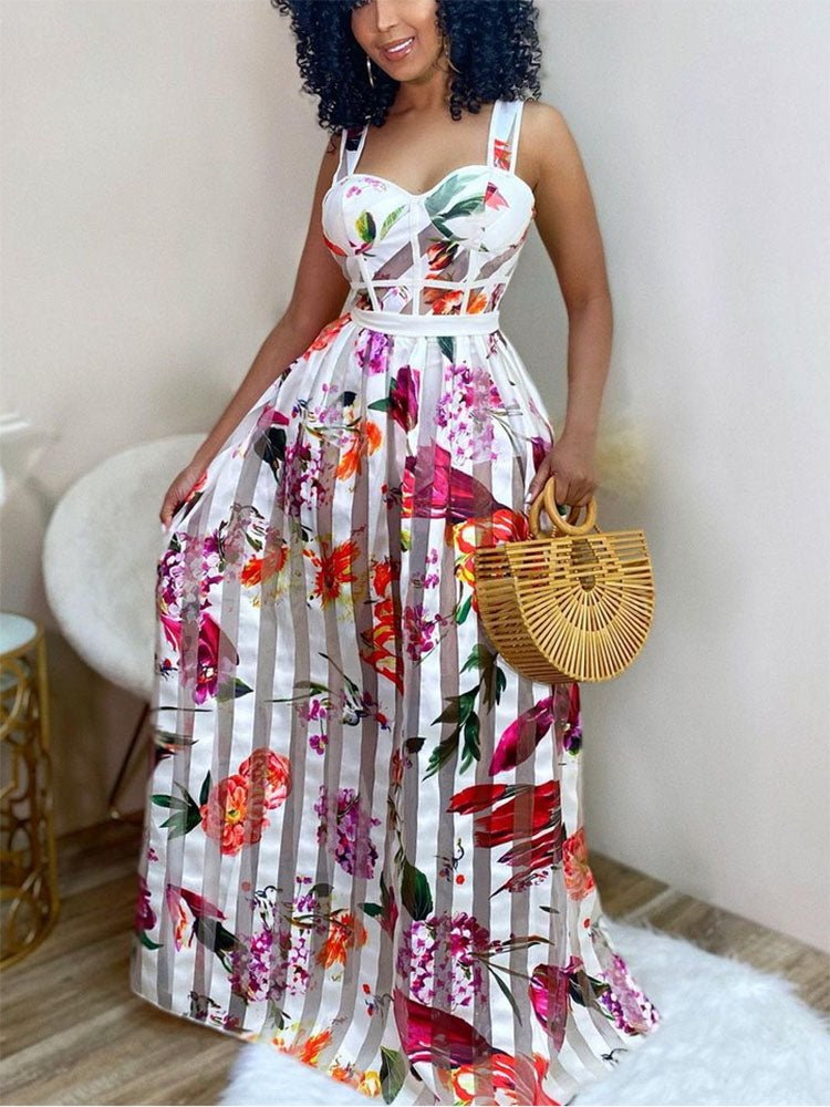 Woman wearing a white maxi dress with a floral print and vertical stripes, holding a bamboo handbag.