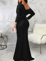 Rear view of a woman wearing a long black asymmetrical dress with long sleeves and a mermaid hemline.