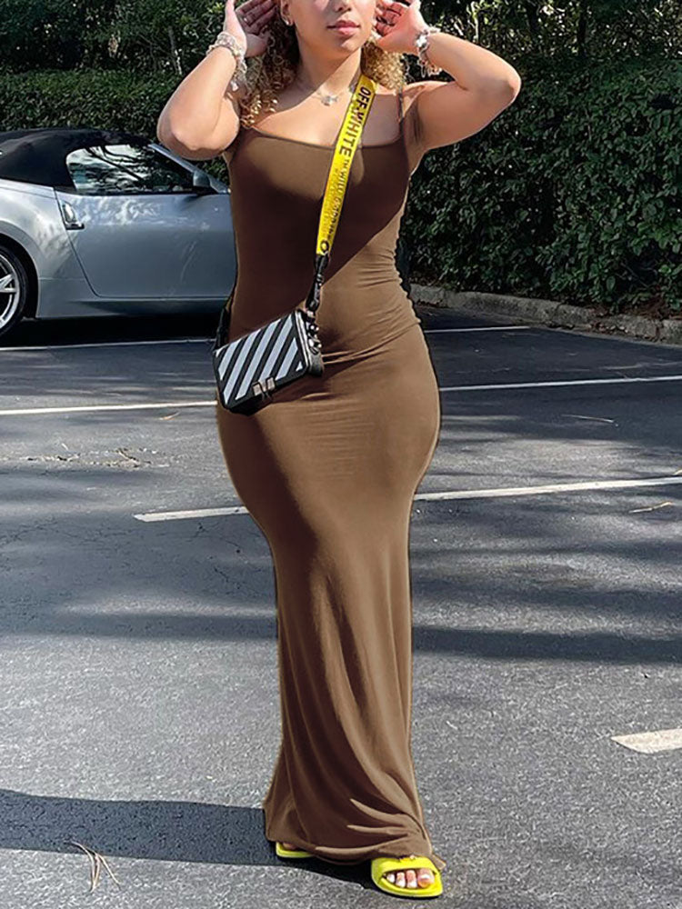 Woman in a brown spaghetti strap maxi dress and a crossbody bag