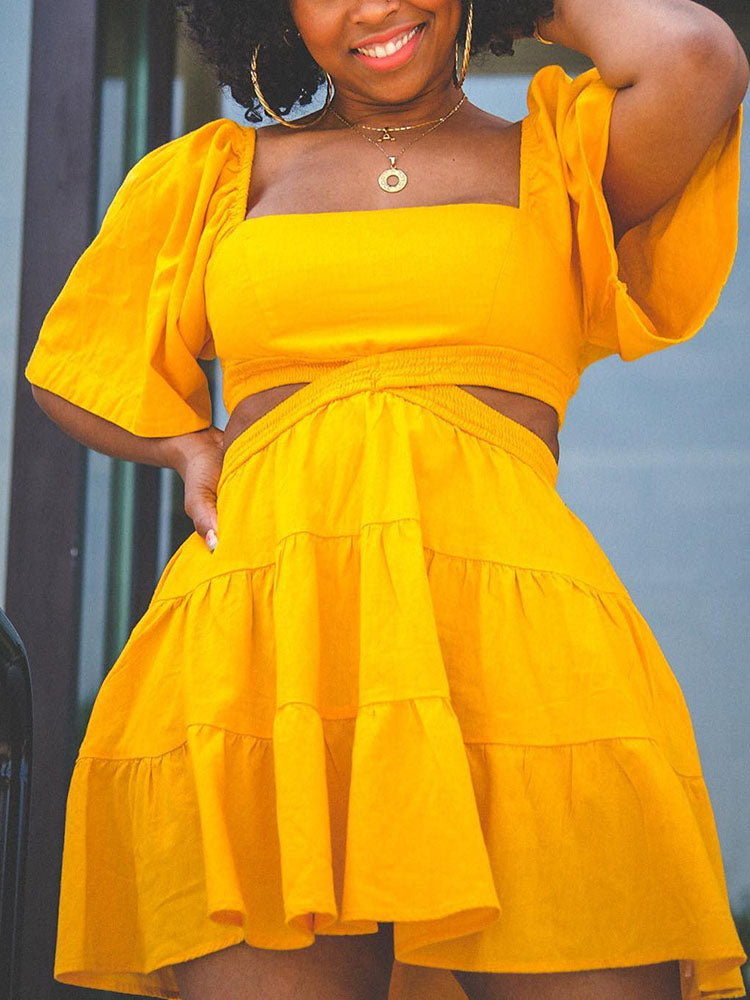 Close-up of a woman's yellow two-piece set featuring a square neckline, cut-out waist, and tiered skirt.