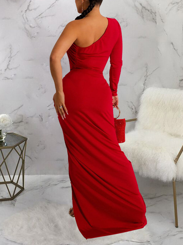 Back view of a woman wearing a red one-shoulder long sleeve ruched maxi dress with a high slit.