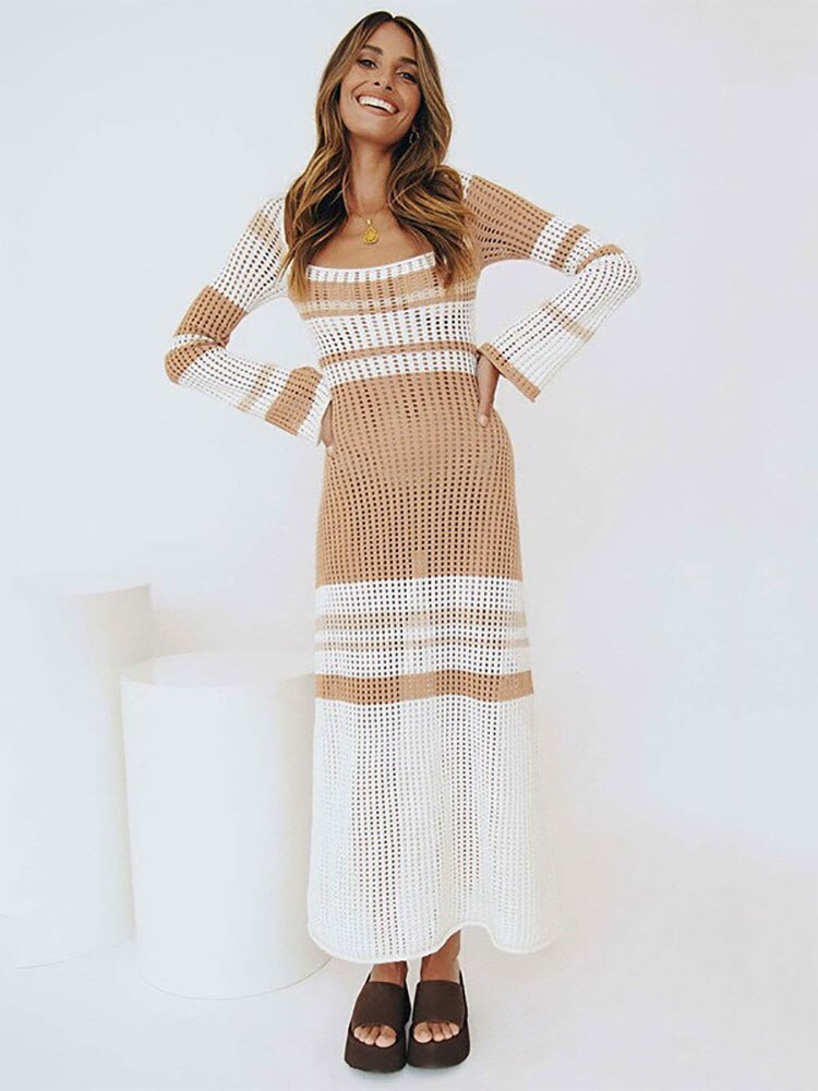 Woman wearing a beige and white striped, crochet knit maxi dress with long sleeves, posing against a white background.
