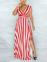 Close-up of a woman wearing a red and white striped maxi dress with a V-neck and high slit, touching her hair.
