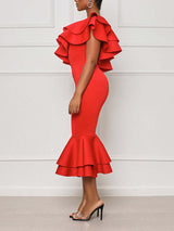 Side view of a woman in a red one-shoulder midi dress with ruffle details and a mermaid hem.