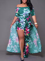 Woman wearing a green floral print off-the-shoulder maxi dress with a high leg slit and integrated shorts.