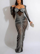 Woman holding a clutch, wearing a long, sheer black embellished dress.