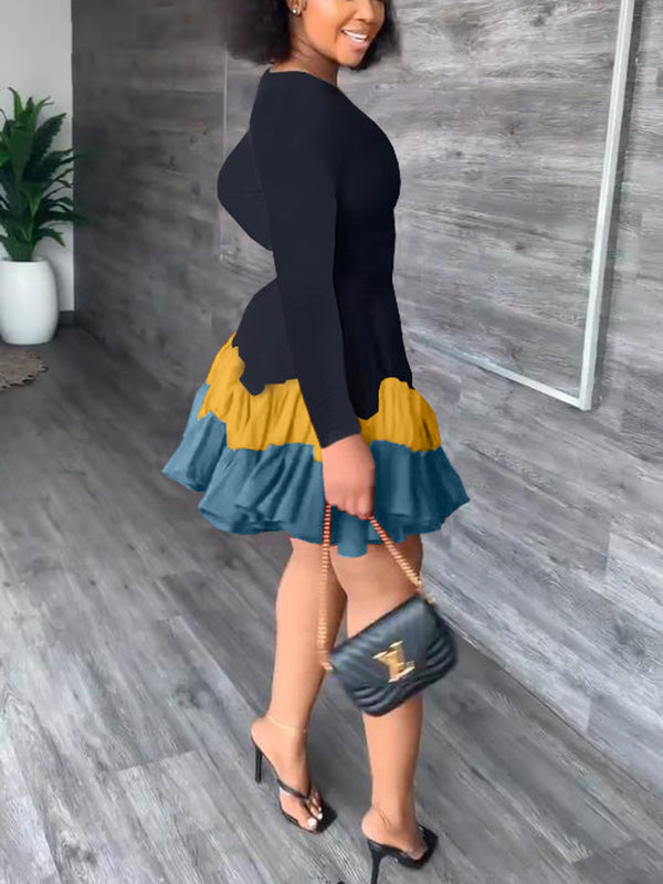 Side view of a woman in a black long-sleeved dress with a tiered, ruffled hem in shades of yellow and blue.