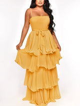 Woman wearing a flowy yellow tiered maxi dress with spaghetti straps and a tie waist.