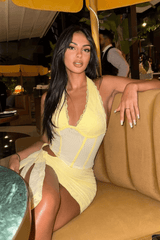 Woman sitting on a couch wearing a yellow mini dress