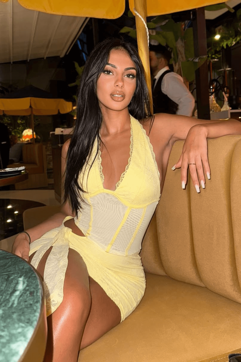 Woman sitting on a couch wearing a yellow mini dress