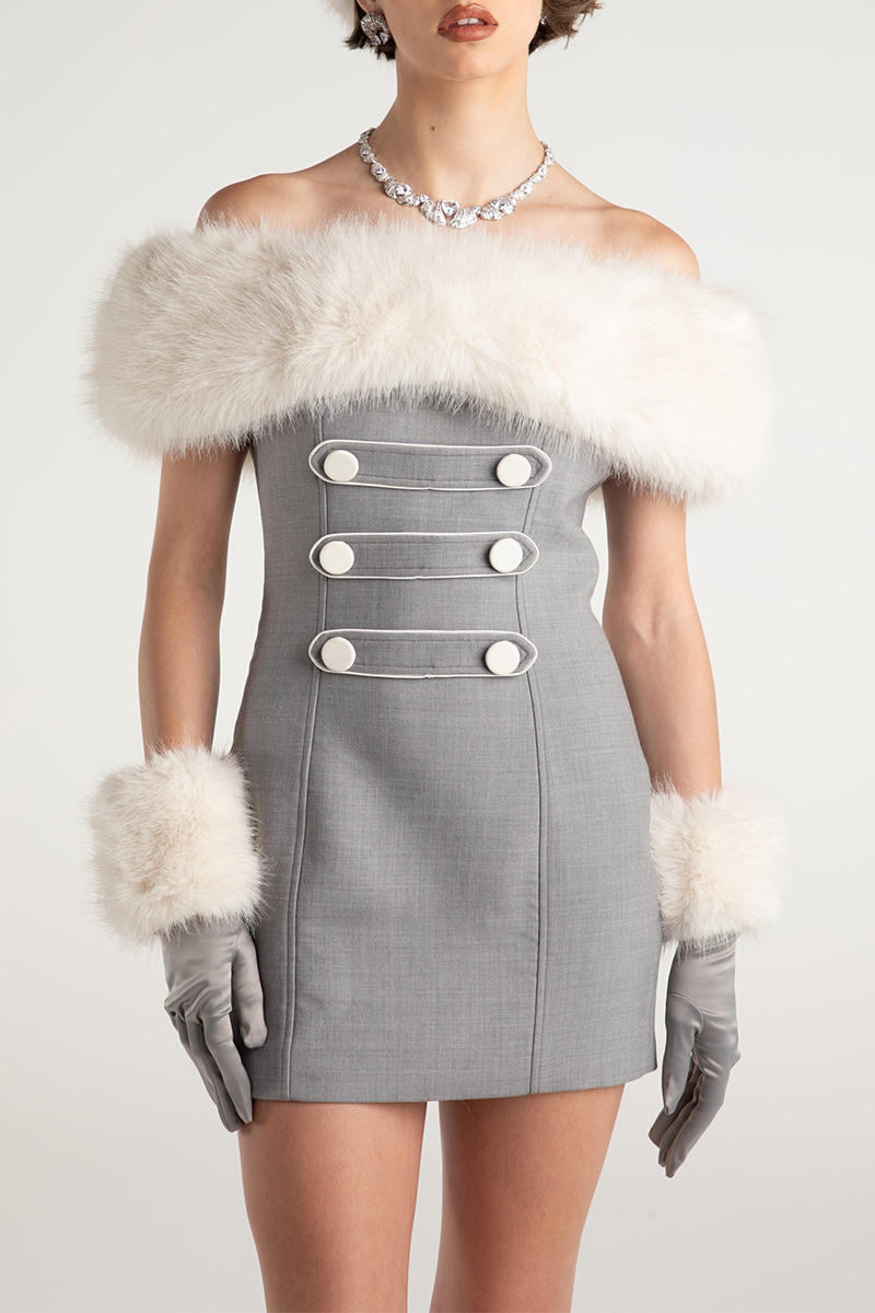Full-body view of a woman in a grey off-the-shoulder mini dress with white faux fur trim and cuffs, grey gloves, and a diamond necklace.