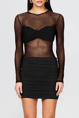 Model wearing a black sheer mesh top with a ruched sweetheart neckline overlay and a black ruched mini skirt.