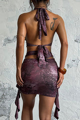 Back view of a woman wearing a short, halter neck dress with a plunging neckline and cut-out details.