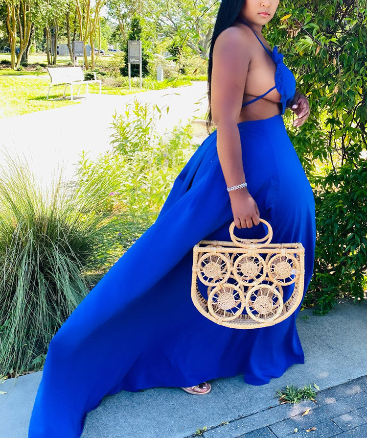 Side view of a woman in a royal blue maxi dress with a halter neckline and cut-out detail.