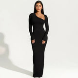 Woman wearing a black long-sleeved maxi dress with an asymmetrical neckline and a high slit, standing against a white background.