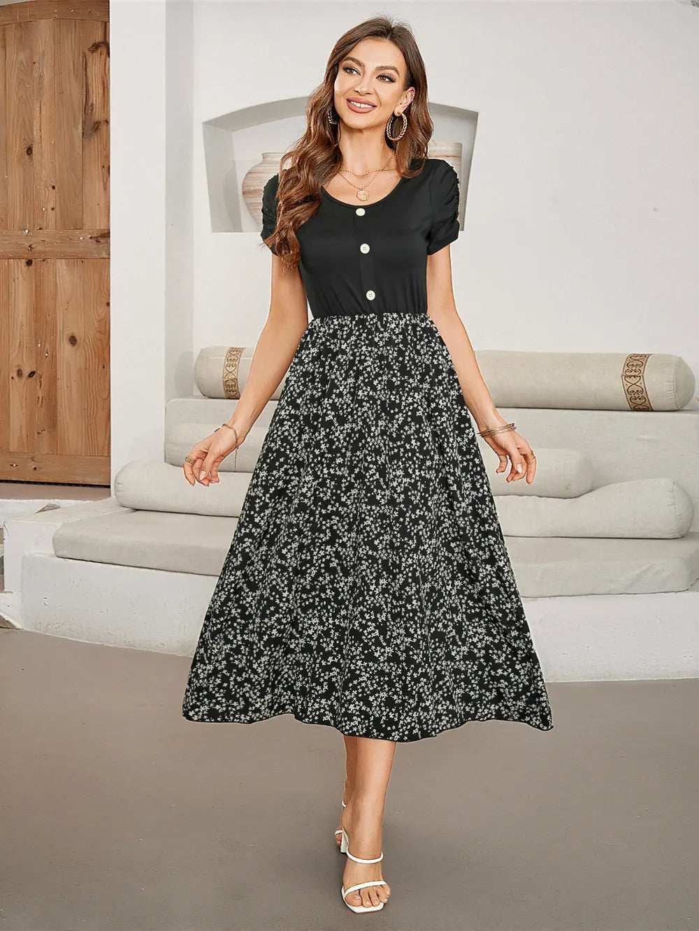 Woman wearing a black short-sleeve top with a floral print midi skirt.
