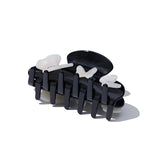 Close-up, angled view of a black claw hair clip featuring white iridescent butterflies and small gem accents.