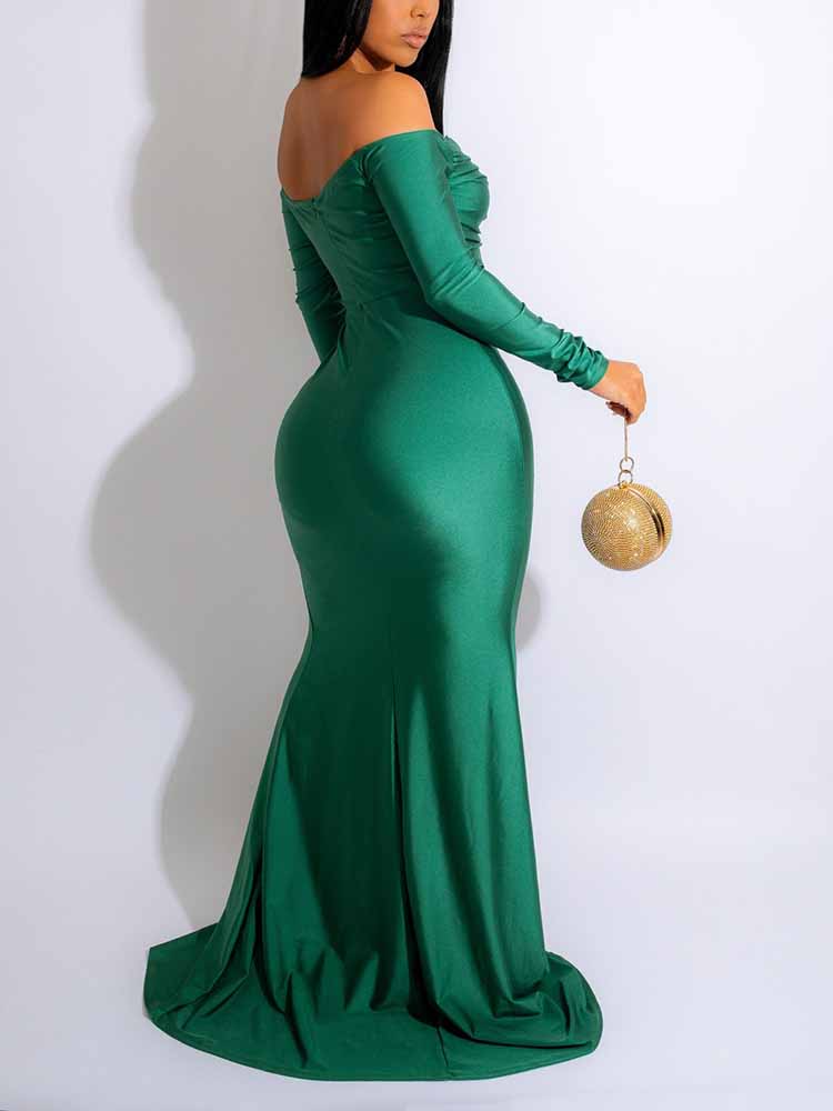 Back view of a woman in a floor-length emerald green off-the-shoulder gown.