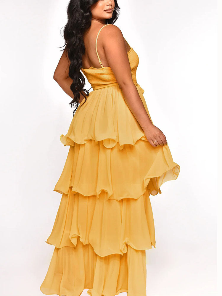 Back view of a woman in a yellow tiered maxi dress with spaghetti straps.