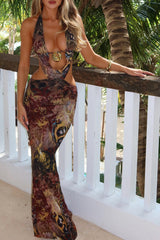 Woman wearing a long, patterned dress with cut-out details and a halter neckline.