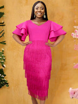 Woman wearing a vibrant pink midi dress with tiered fringe and ruffled sleeves, standing against a yellow textured background.