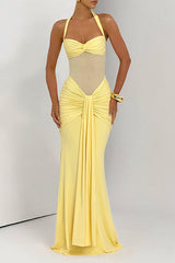 Woman wearing a yellow floor-length gown with a halter neckline, sheer midriff, and ruched detailing.