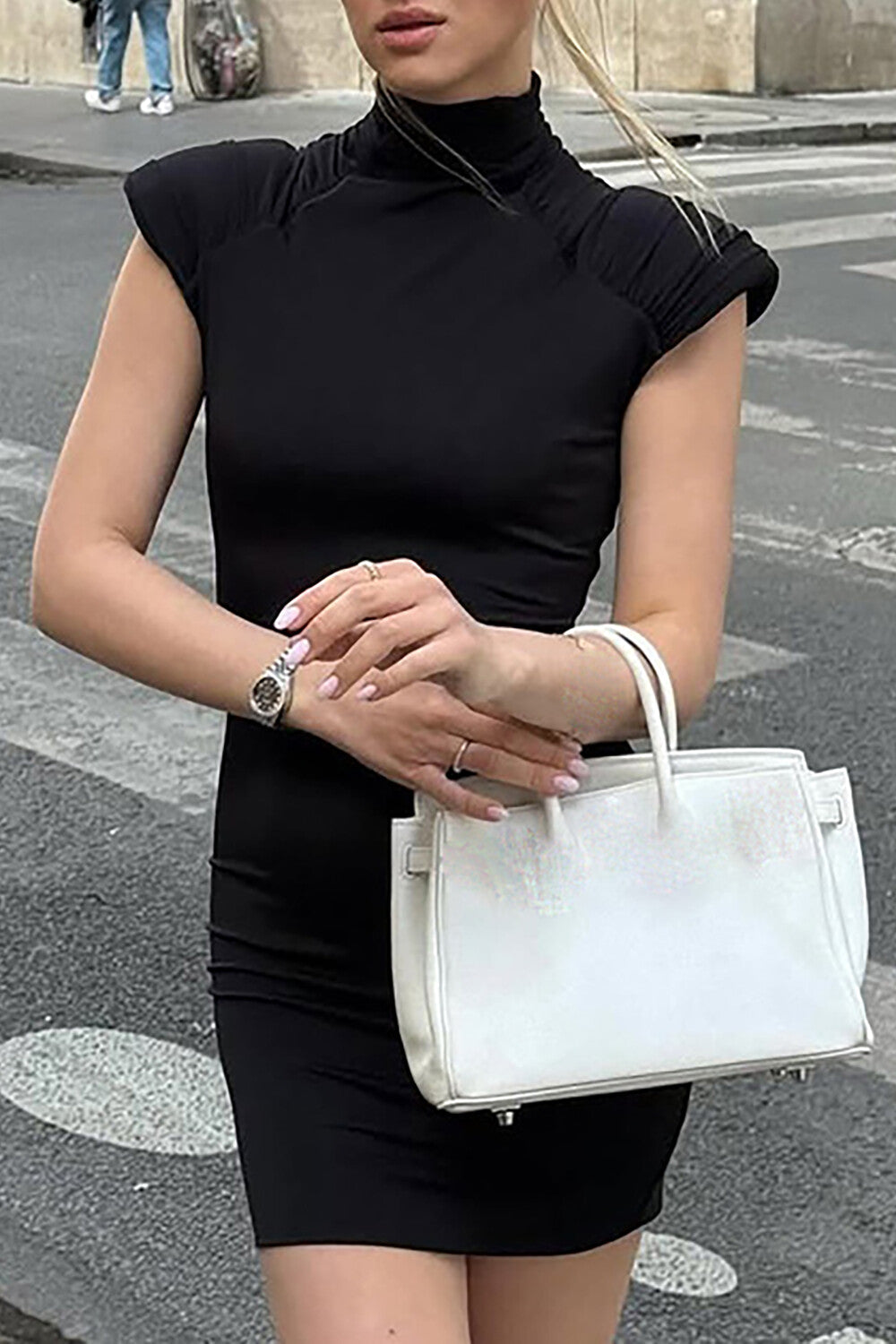 woman in a black fitted dress holding a white handbag