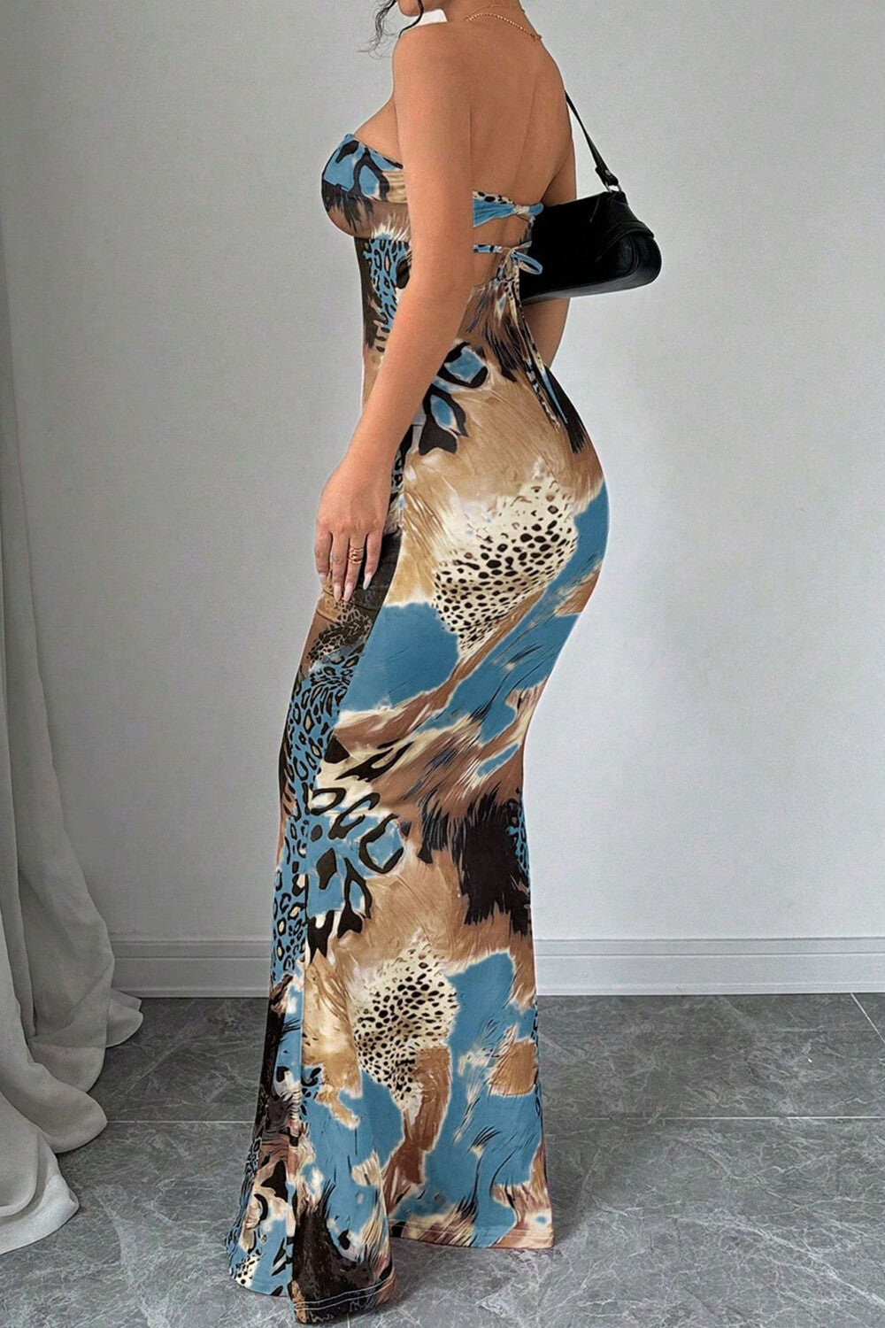 Side view of a woman in a strapless abstract print maxi dress.