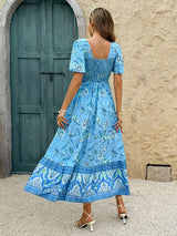Back view of a woman in a blue floral print midi dress, showing the smocked back detail.