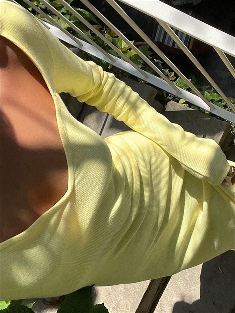 Close-up of the chest and sleeve of a woman in a yellow ribbed knit maxi dress.