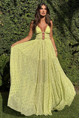 Woman wearing a lime green maxi dress with gold polka dots and a plunging neckline, standing outdoors.