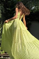 Back view of a woman in a lime green tiered maxi dress with gold polka dots.