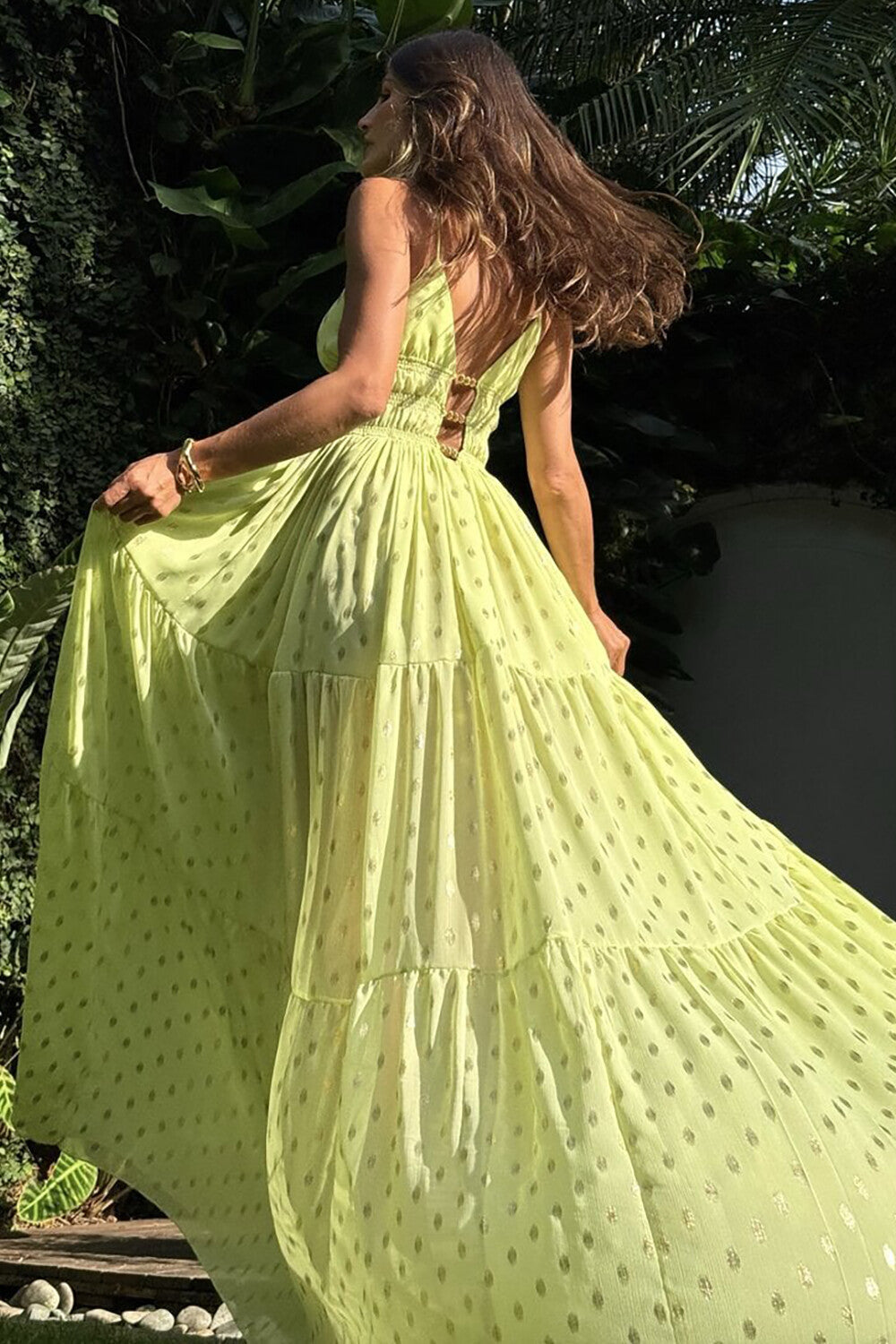 Back view of a woman in a lime green tiered maxi dress with gold polka dots.