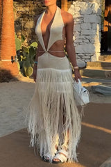 Woman wearing a white halter maxi dress with cut-out details and fringe hem