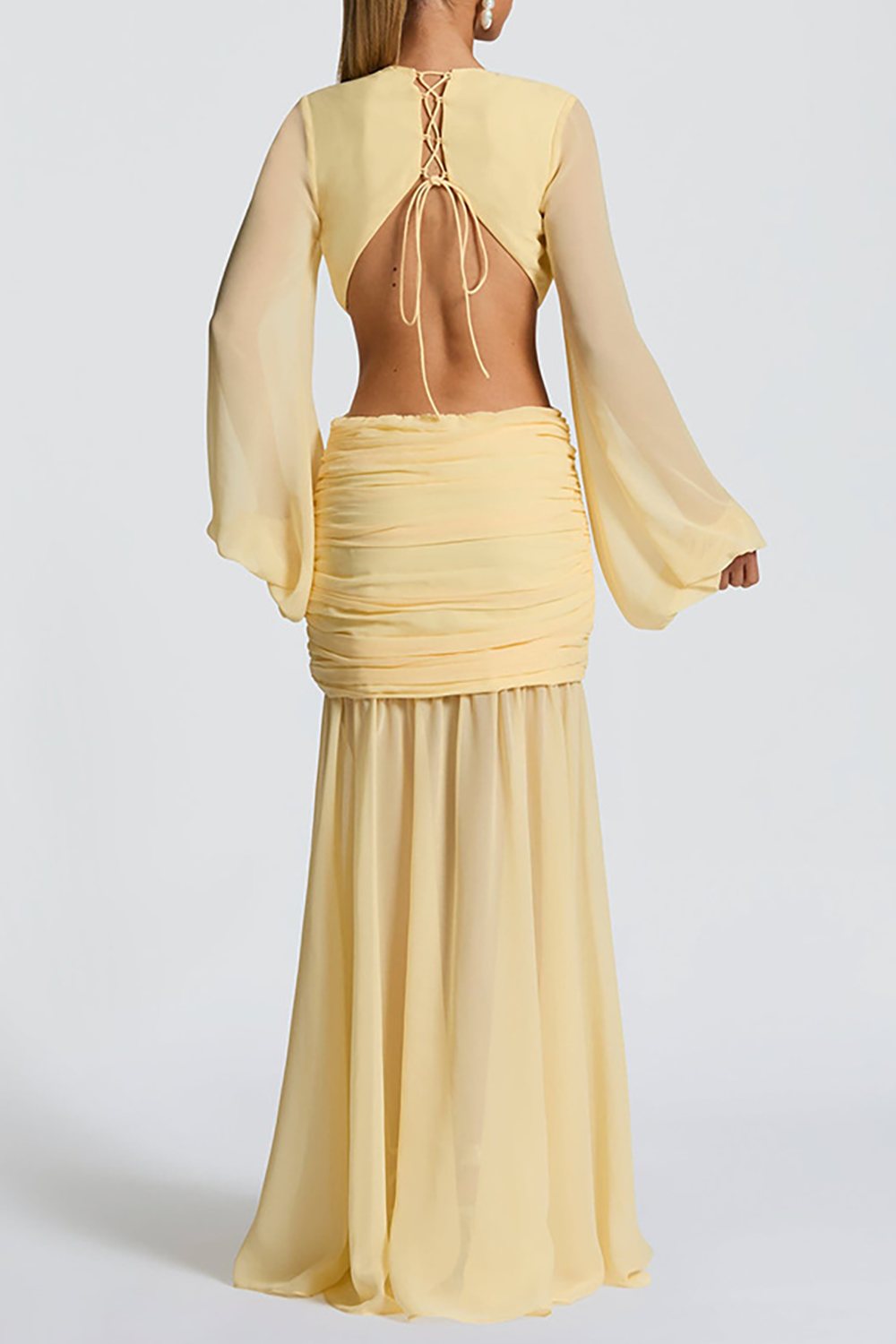 Back view of a yellow dress with an open back secured by a lace-up tie, long balloon sleeves, and a ruched skirt.