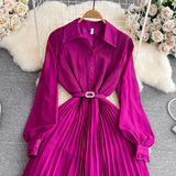 Close-up of a magenta pleated midi dress, showing the button-up bodice and belted waist.