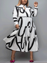A woman wearing a white midi dress with a bold black graphic print and clear heels with pink bows, posing against a grey background.