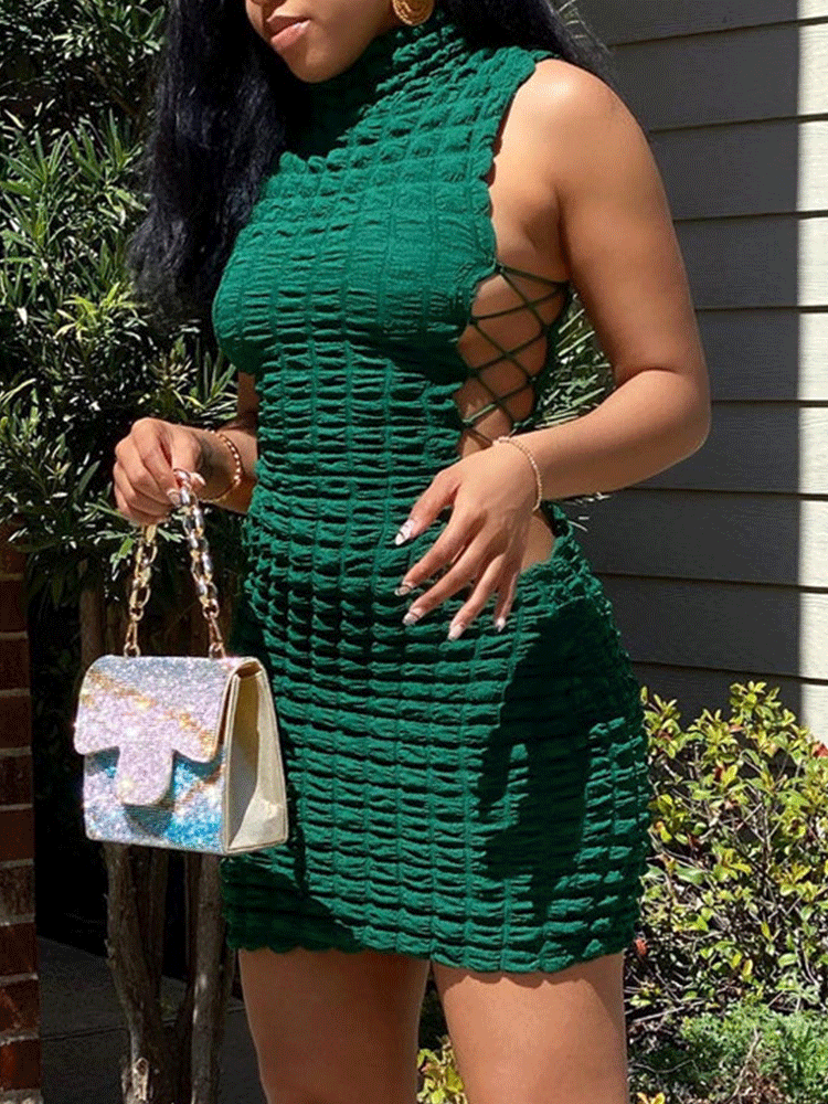 Woman wearing a green sleeveless textured knit bodycon dress with lace-up sides and a turtleneck