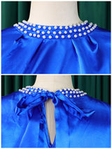 Close-up of the pearl embellishment on the neckline and the bow closure at the back of the royal blue satin dress.
