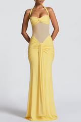 Woman wearing a floor-length yellow halter dress with ruched detailing and a sheer bodice, front view