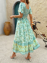 Back view of a woman in a light green floral print midi dress with a smocked bodice.