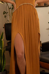 Close-up of the high leg slit on a rust-colored maxi dress worn by a woman.