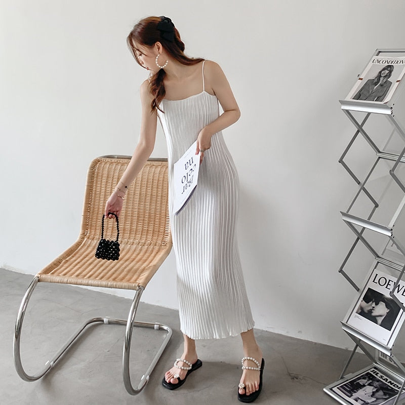 woman wearing a white pleated slip dress and pearl-embellished sandals