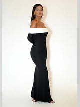 Side view of a woman in a black off-the-shoulder floor-length dress with a white trim.